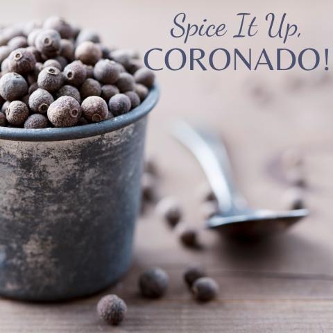 A photograph of a small cup full of allspice berries with some berries on the surface next to the cup and a spoon. Text reads: Spice It Up, Coronado!